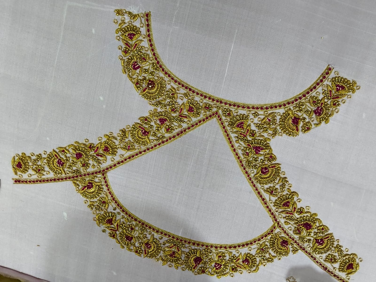 Embroidered blouse panels laid out flat in gold and maroon before assembly