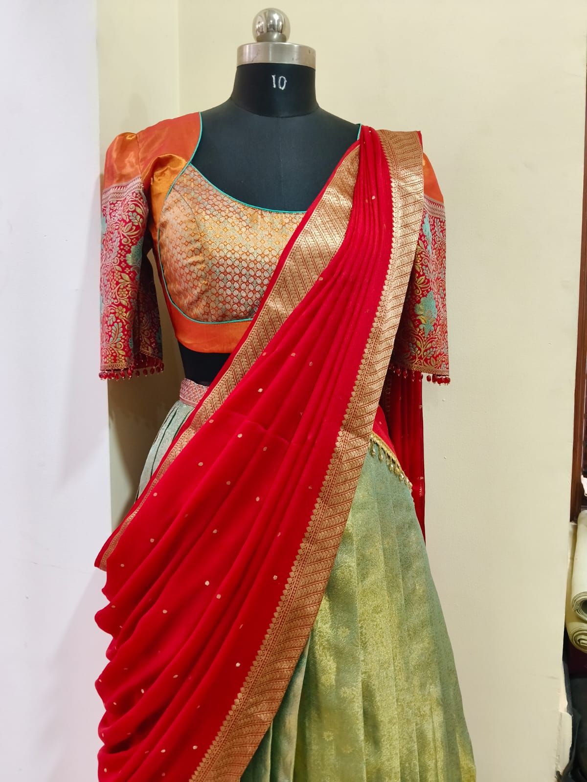 Half-saree with an orange brocade blouse, red dupatta and sage-green skirt