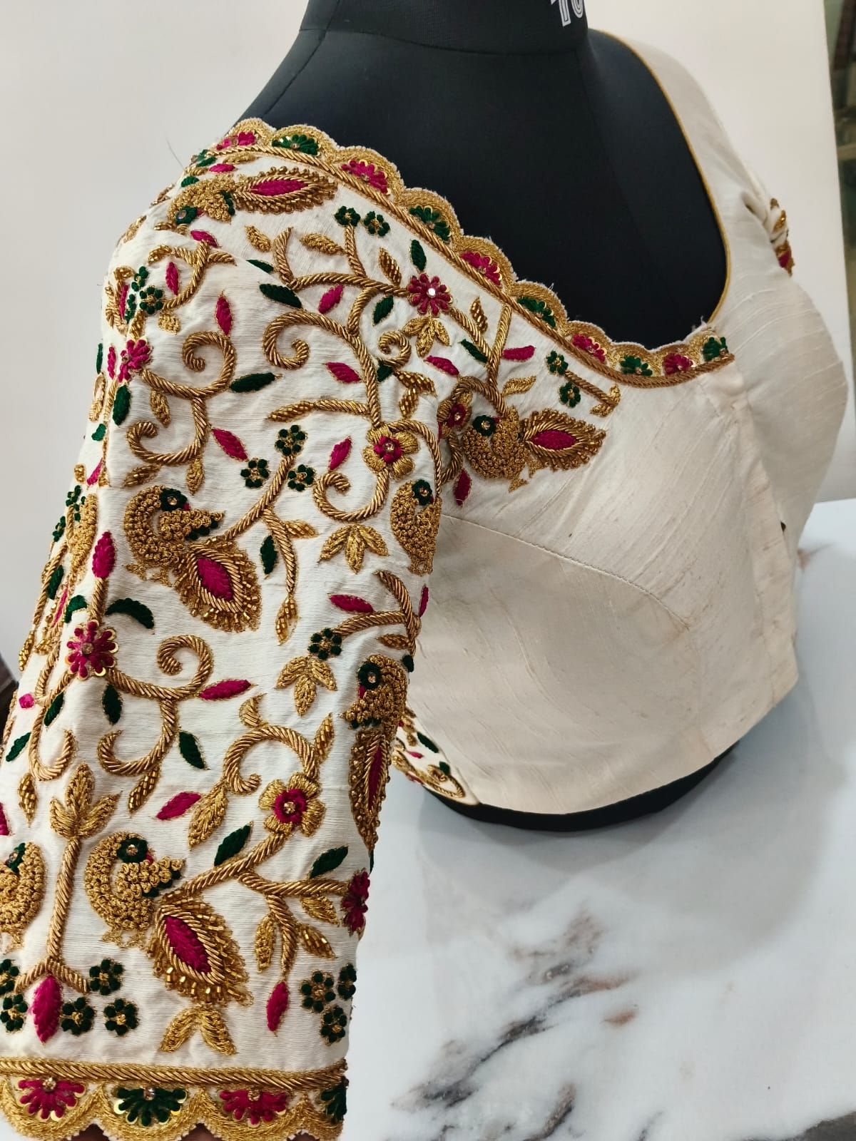 Ivory blouse sleeve embroidered with gold peacocks and vines