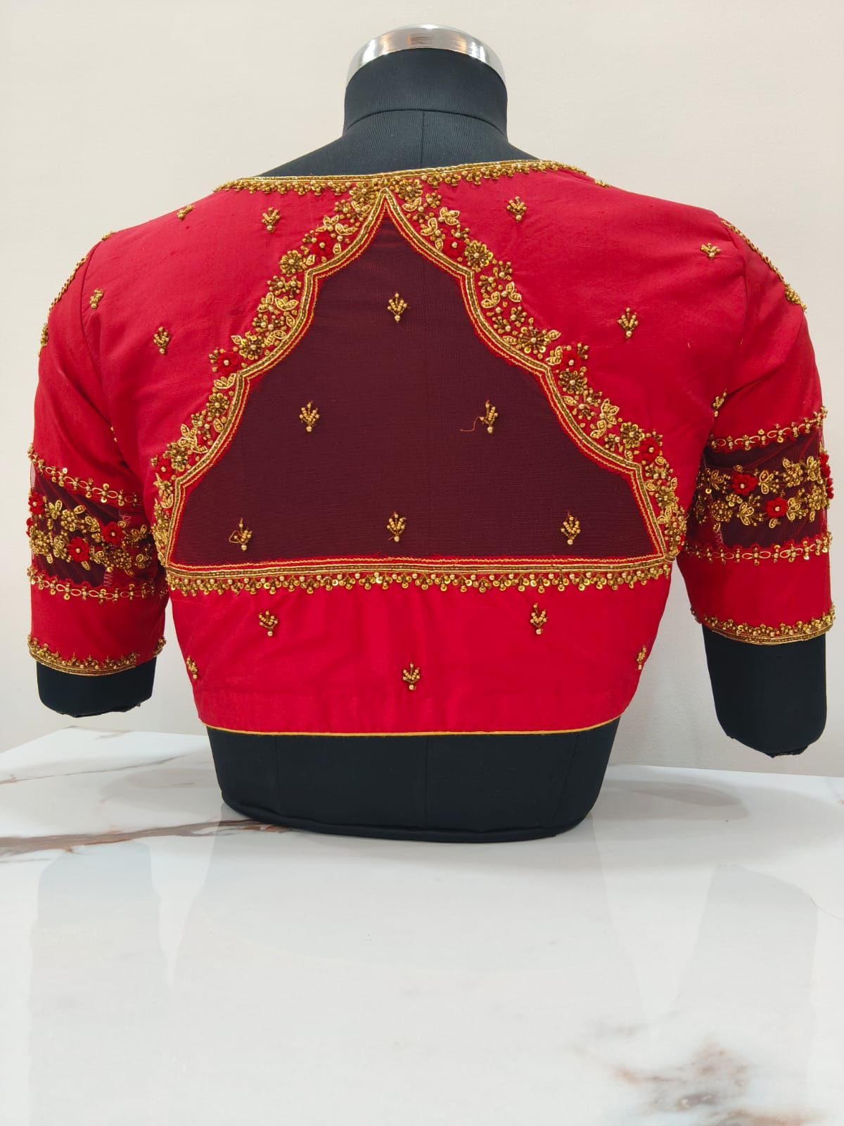Red bridal blouse with a sheer net back framed in scalloped gold zardosi
